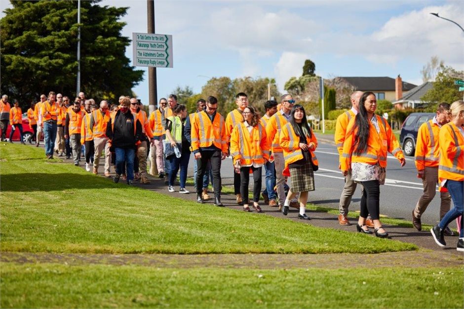Photo of approximately 30 people from the Eastern Busway Alliance project team wearing orange high vis vests walking along a footpath on Reeves Road Photo of approximately 30 people from the Eastern Busway Alliance project team wearing orange high vis vests walking along a footpath on Reeves Road